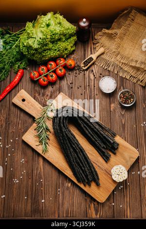 Smoked meat sticks or kabanos and spices on a rustic board, ideal for gourmet food presentations Stock Photo