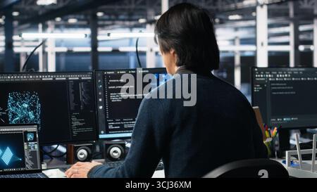 Software developer entering server room office, using AI to review infrastructure diagnostics. System administrator in data center analyzes performance data using artificial intelligence tech Stock Photo
