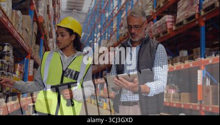 Warehouse workers in vests scanning stock in warehouse aisle, with scanner and tablet. Logistics, inventory, technology, industrial, collaboration, ef Stock Photo