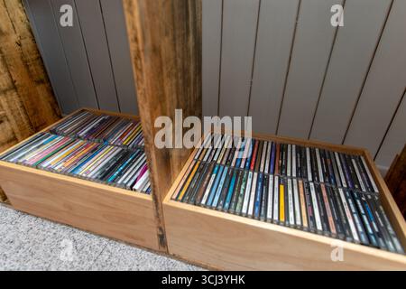 Neatly arranged CD albums in a custom wooden shelf, showcasing a personal music library against a clean paneled wall background. Stock Photo