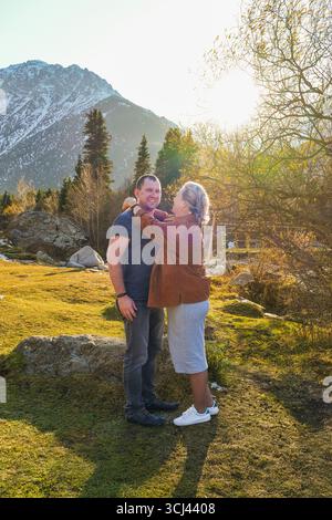 A man and a woman embracing lovingly in a beautiful autumn mountain landscape under a bright, clear sky. Stock Photo