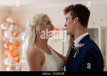 Bride and groom sharing joyful moment, smiling and embracing at wedding celebration Stock Photo