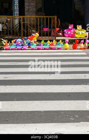 Colorful inflatable toys on the side of the road and a zebra crossing path. Stock Photo