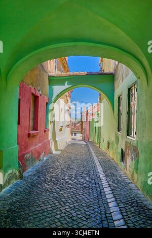 Tunneled cobblestone pedestrian footpath beside colorful house exteriors in the old town center of Sibiu city, Sibiu, Transylvania, Romania, Europe Stock Photo