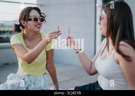 Young women enjoying a snack and laughing during a rooftop hangout Stock Photo