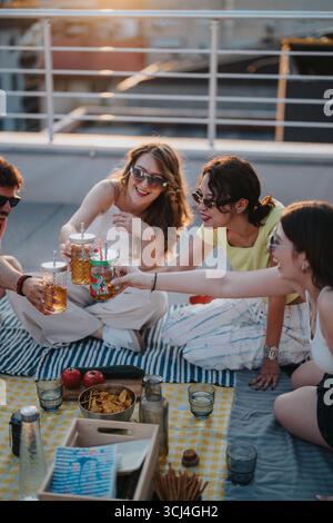 Group of friends enjoying a rooftop party at sunset with drinks Stock Photo