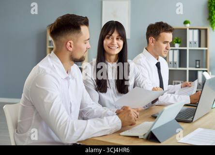 Smiling colleagues discussing documents in a collaborative meeting at work Stock Photo