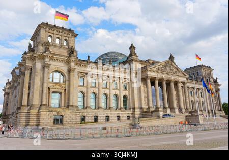 Berlin, Germany - August 20, 2025: Exterior view of the Reichstag Building in Berlin, featuring classical architecture, flags, and a cloudy sky. Stock Photo