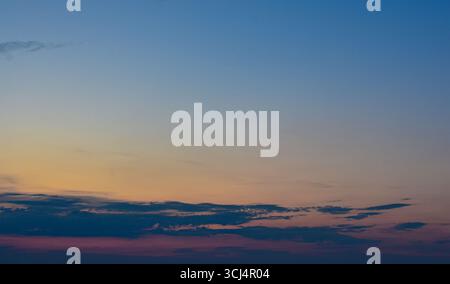 Sky during sunset with magical warm colors and soft clouds glowing beautifully, no land or horizon visible in the frame. Stock Photo