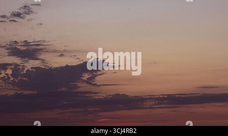 Softly lit clouds during a magical sunset, bathing the sky in warm tones, captured without land or objects in sight. Stock Photo