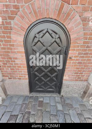 Wooden gothic door with red brick wall front view Stock Photo