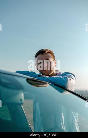 Man leaning on car roof outdoors Stock Photo