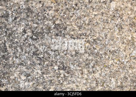 Detail of rough, worn, and dirty natural granite stone with dark and light gradients. Stock Photo