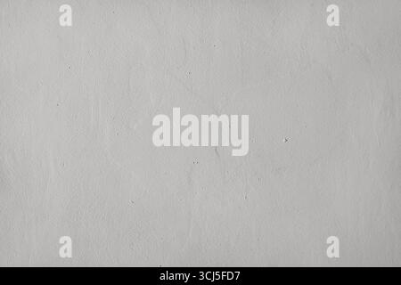 Detail of a smooth, irregular stuccoed wall with grey imperfections. Front view. Stock Photo