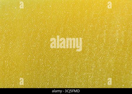 Background detail of the texture of a synthetic yellow sponge with many tiny holes, for cleaning or hygiene. Top view. Stock Photo