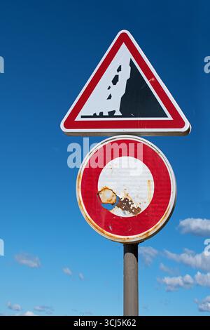 Warning of falling rocks. Old sign with rust against a blue sky Stock Photo