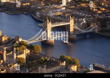 Tower Bridge, London. A boat travels on the Thames River near the Tower of London at sunset. Stock Photo
