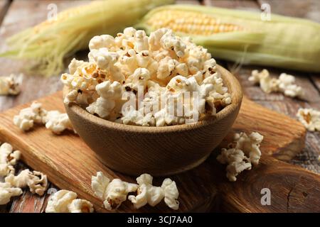 Tasty popcorn and corncobs on wooden table, closeup Stock Photo
