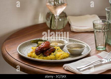 Grilled sausages with mashed potatoes and herbs on table in restaurant.  Two chorizo sausages with mashed potato. Stock Photo