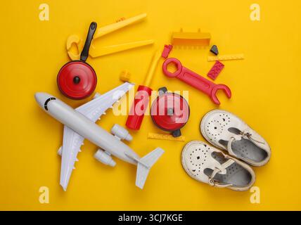 flat lay composition of children's sandals and toys on yellow background. Top view Stock Photo