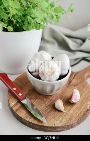 Garlic Cloves and Bulb in ceramic bowl on wooden cutting board closeup Stock Photo