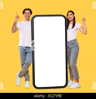Couple standing next to big white empty smartphone screen Stock Photo