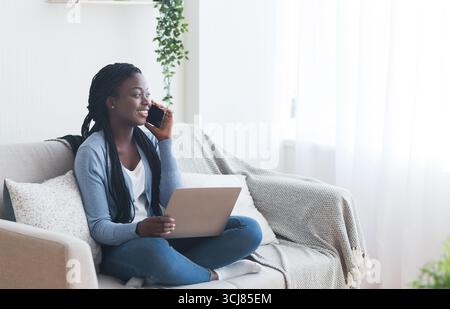 Woman talking on phone and using laptop, searching job online Stock Photo