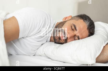 Man Sleeping Peacefully on a White Pillow in Bed Stock Photo