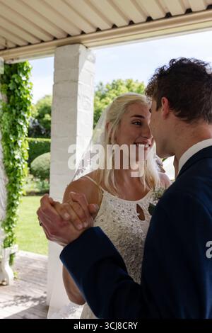 Bride and groom dancing joyfully under pergola, sharing loving moment Stock Photo