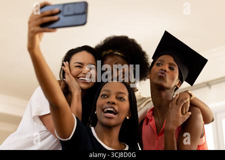 Friends celebrating graduation taking selfie together, smiling and enjoying moment Stock Photo