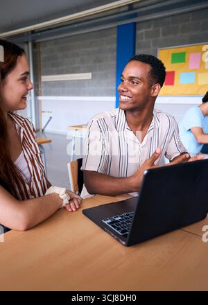 High school students collaborating on project with laptop in classroom Stock Photo