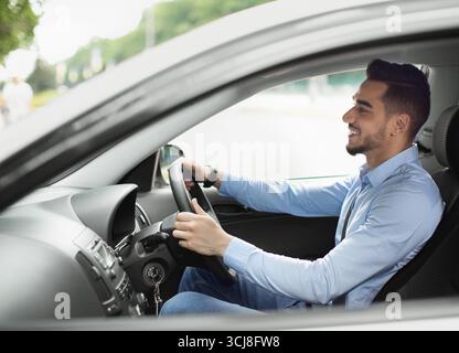 Attractive arabic guy enjoying driving, going to job Stock Photo