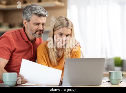 Attractive middle aged spouses working from home Stock Photo