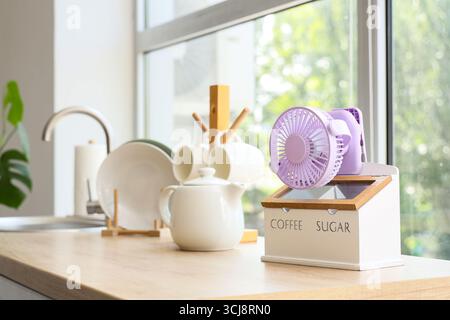 Lilac mini fan on box for coffee and sugar in kitchen Stock Photo
