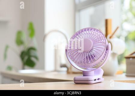 Lilac mini fan on table in kitchen, closeup Stock Photo