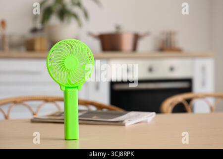 Green mini fan on table in kitchen, closeup Stock Photo