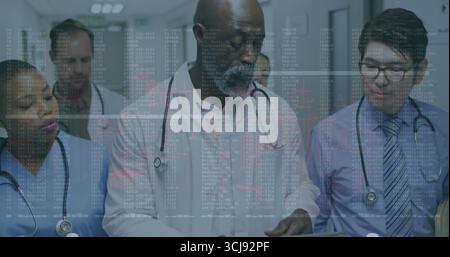 Walking medical team reviewing medical records in hospital corridor, with tablet, stethoscopes Stock Photo