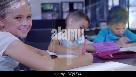 Smiling schoolgirl wearing striped shirt sitting at school desk, with pink pencil case, copy space Stock Photo
