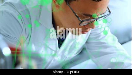Analyzing scientist wearing lab coat and glasses leaning over lab bench, with molecular overlay Stock Photo