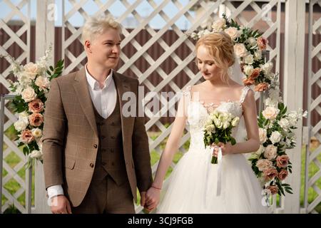 Couple exchanging vows during outdoor wedding ceremony in sunny garden Stock Photo