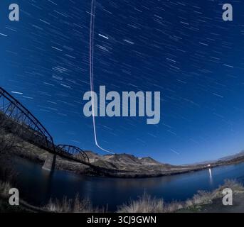 A bridge spans a river with a clear night sky above Stock Photo
