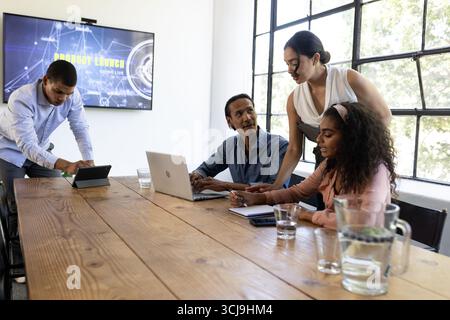 Diverse business team collaborating on project with laptops in modern office Stock Photo