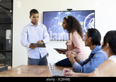 Collaborating in office meeting, business team using digital tablets discussing strategy Stock Photo