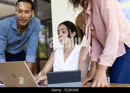 Business team collaborating on laptop and tablet in modern office setting Stock Photo