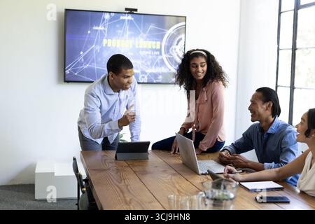 Diverse team discussing project strategy with laptops in modern office meeting Stock Photo