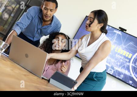 Business team collaborating on laptop in modern office, discussing project details Stock Photo