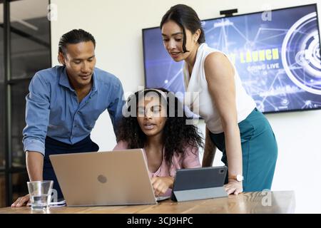 Collaborating in office, diverse team discussing project on laptop and tablet Stock Photo