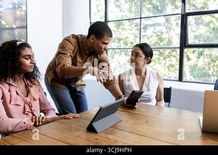 Collaborating in office, business team using tablets discussing strategy during meeting Stock Photo