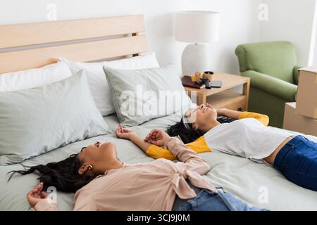 Relaxing at home, two women laughing and enjoying time together on bed Stock Photo