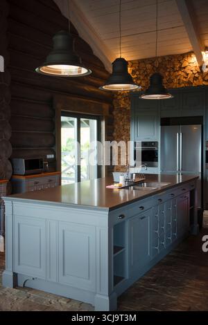 Rustic kitchen with blue island, pendant lights, and wood accents. Stock Photo